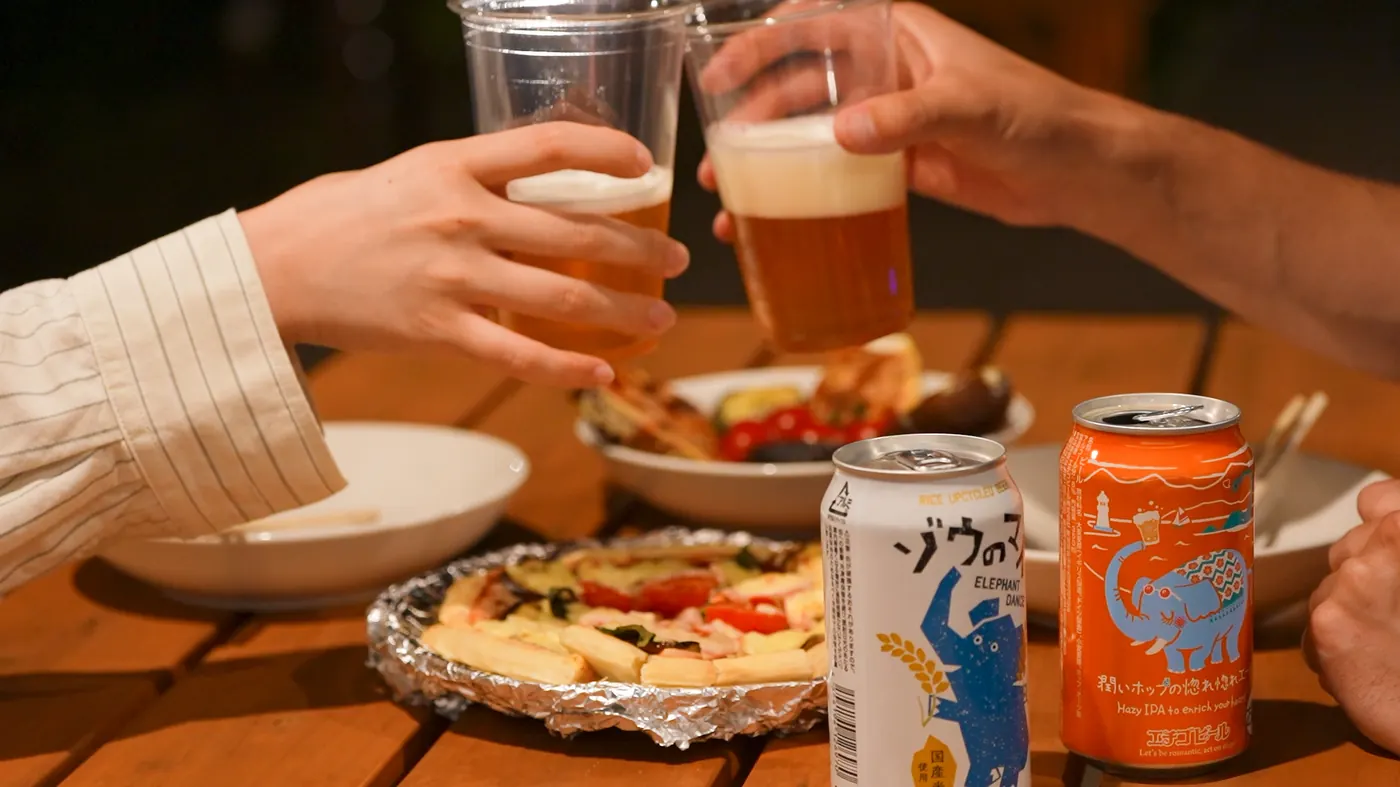 ウッドテーブルでピザとビールで乾杯する手元