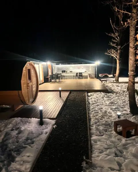 雪の夜にライトアップされた共用キッチンとバレルサウナ