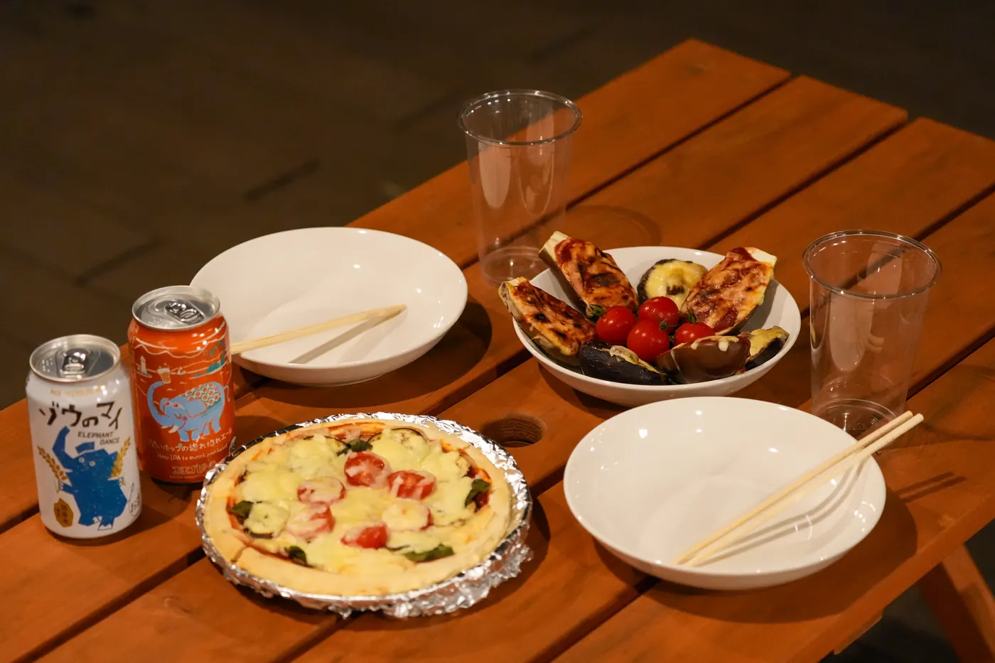 ウッドテーブルに並んだピザと飲み物、紙皿