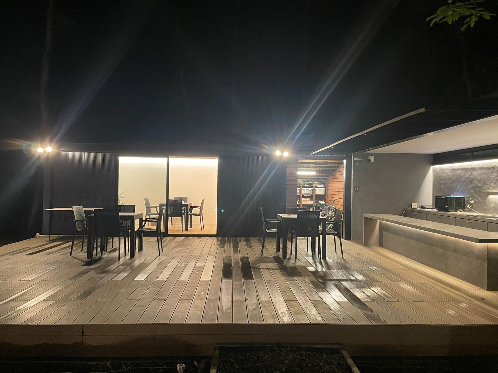 夜の共用テラス。照明に照らされたテーブル席と屋外キッチン