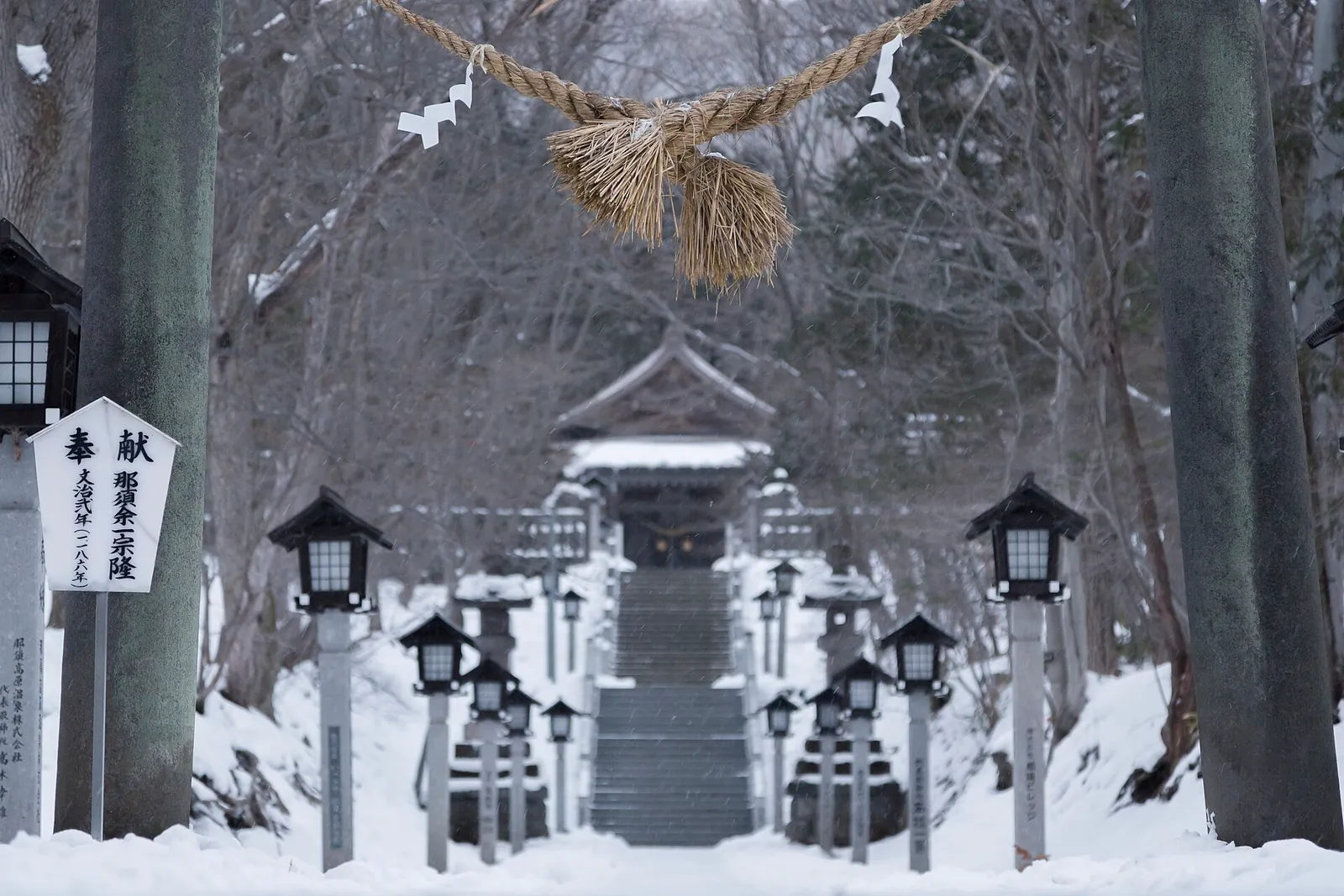 雪に覆われた那須温泉神社の参道。しめ縄と灯籠が並ぶ石段
